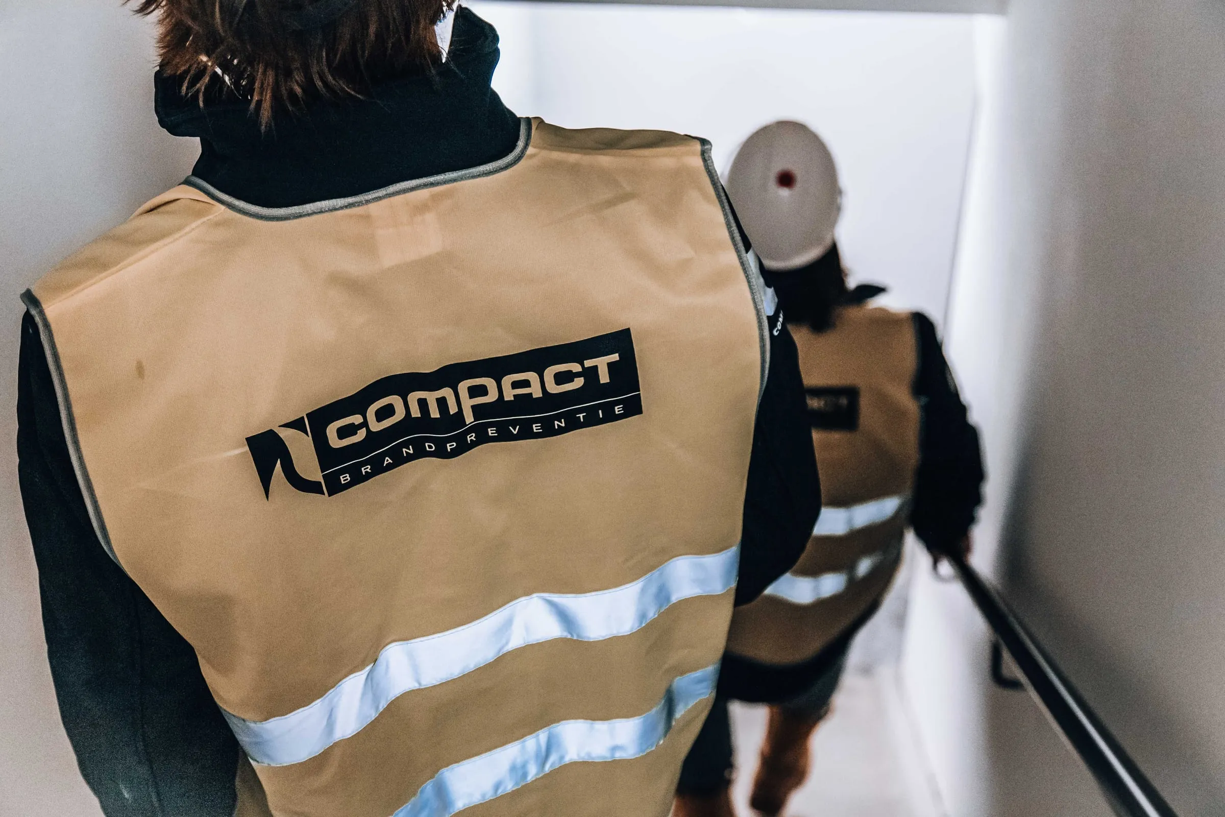 Twee collega's in Compact-hesjes lopen een trappenhuis af